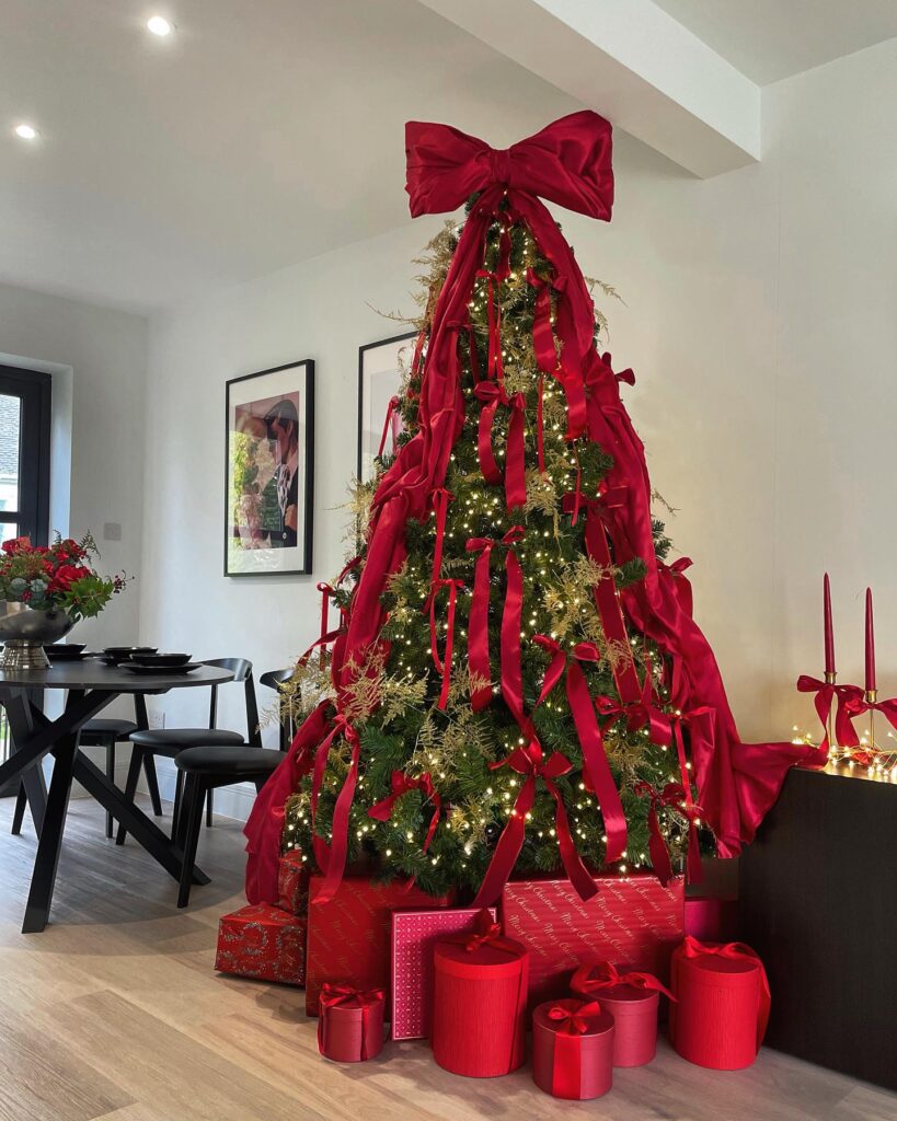 Ρομαντικό χριστουγεννιάτικο δέντρο με μεγάλους φιόγκους σε κόκκινο και καρώ - Η νέα τάση που αντικαθιστά τις μπάλες